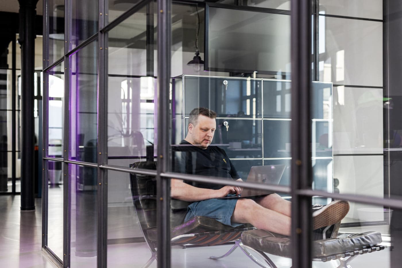 John, MUUUH!-Mitarbeiter, in entspannter Pose in der modernen Büro-Lounge