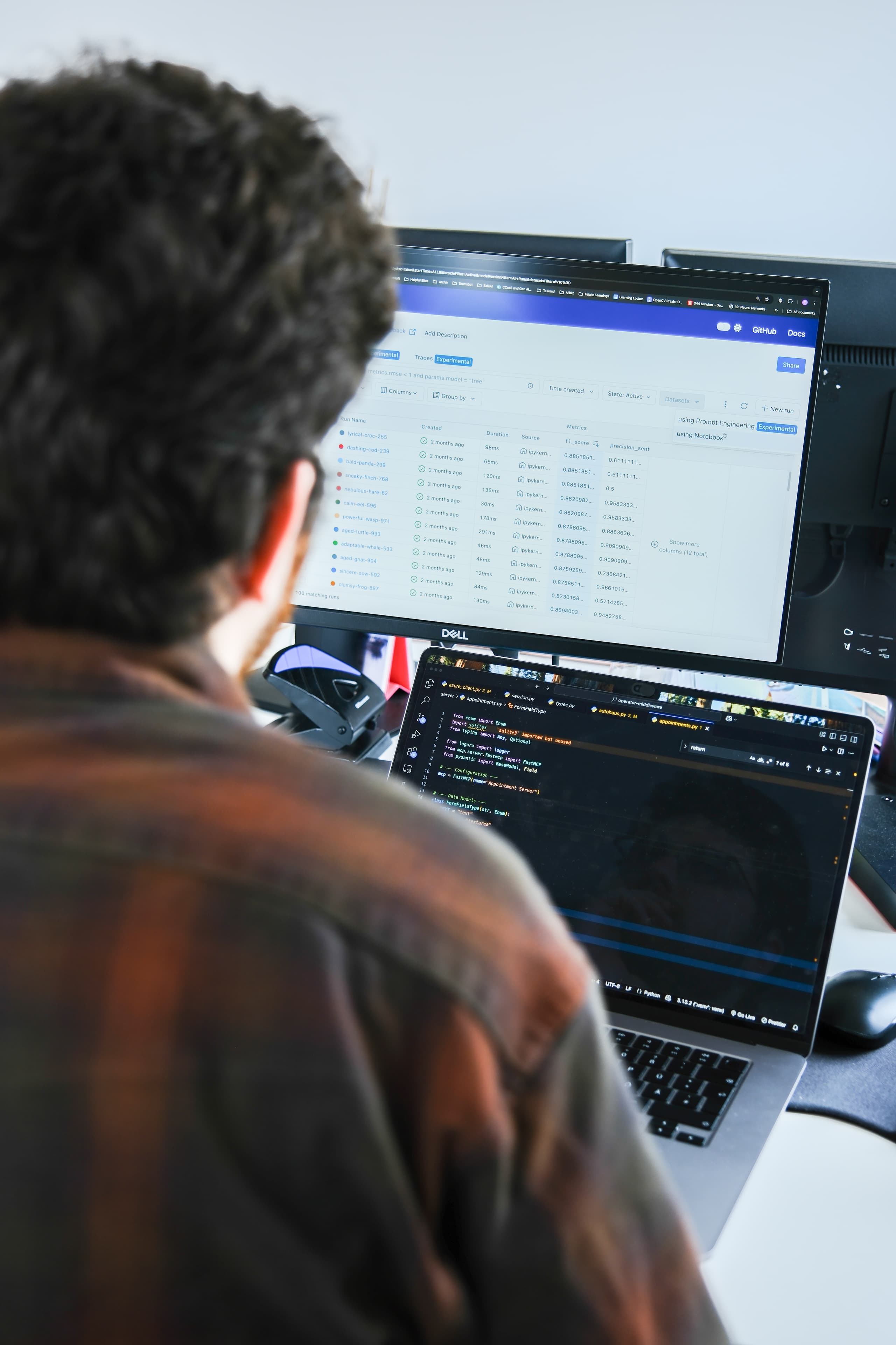 Person bei der Softwareentwicklung an einem Laptop mit zwei Bildschirmen