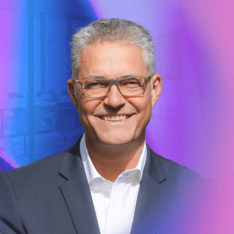 Carsten Wirths lächelt freundlich vor buntem Hintergrund mit farbigen Lichtern