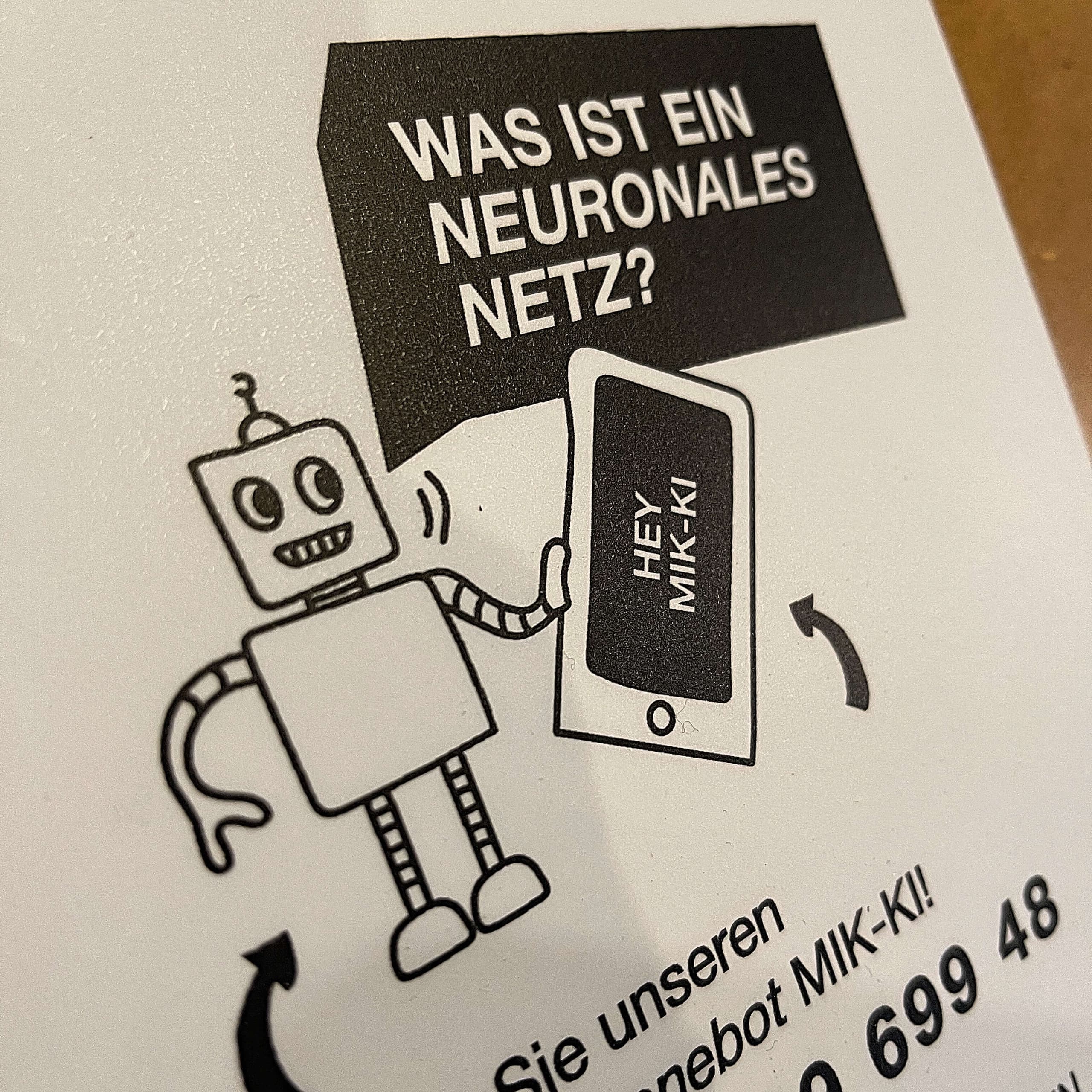 Roboter mit Smartphone fragt: 'Was ist ein neuronales Netz?' – MIK-KI Phonebot zur KI-Ausstellung