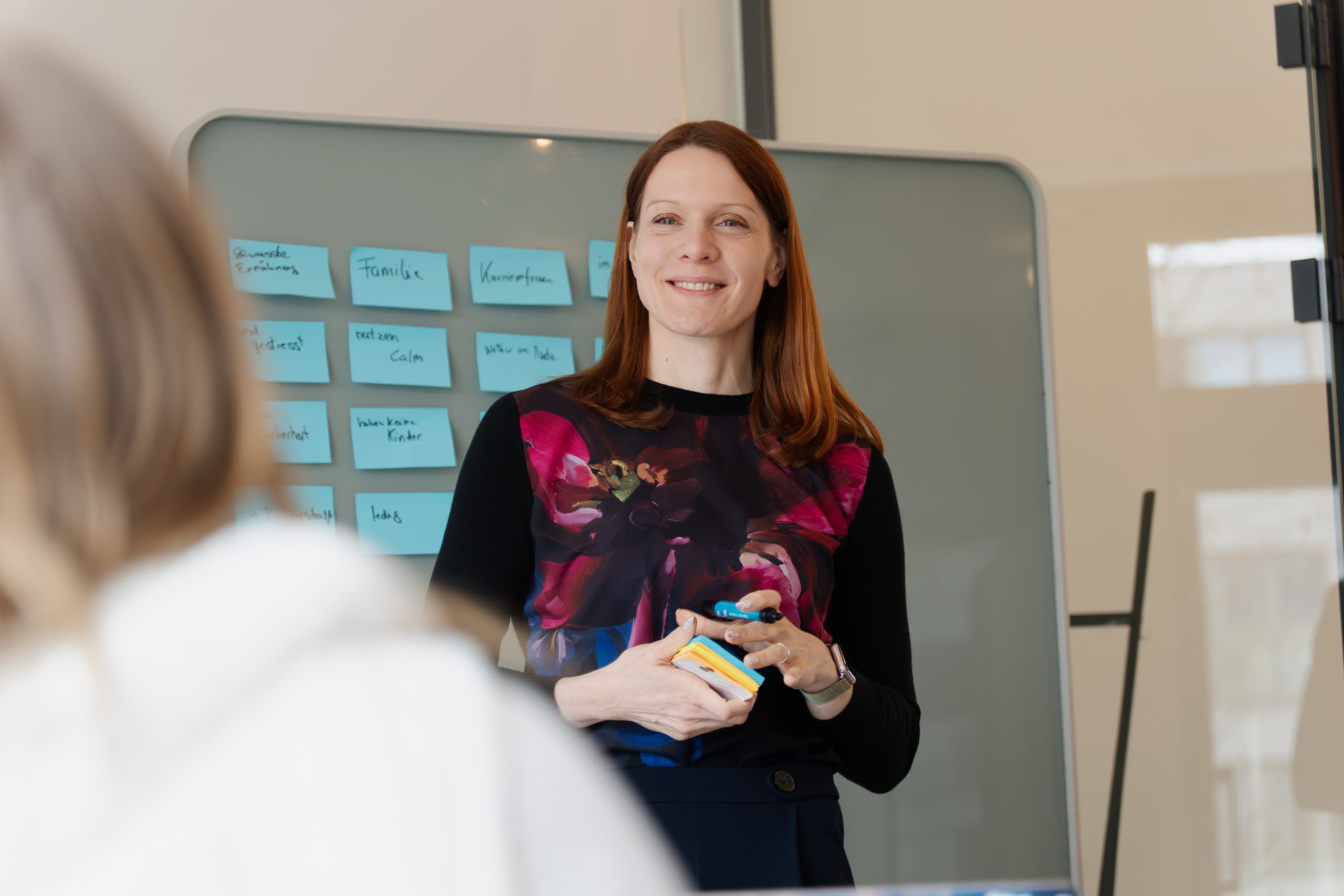 Workshop-Moderatorin präsentiert Ergebnisse vor einem Board mit blauen Post-its