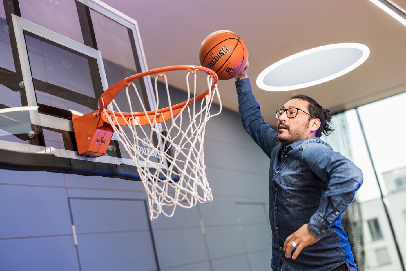 Mitarbeiter Patricio beim Basketball-Korbwurf im lichtdurchfluteten Hageloft-Büro