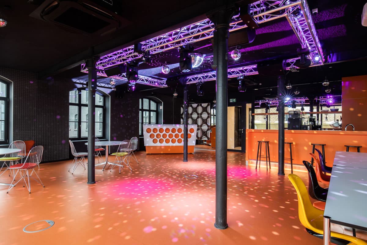 Moderner Event-Raum mit lila Beleuchtung und industriellem Design