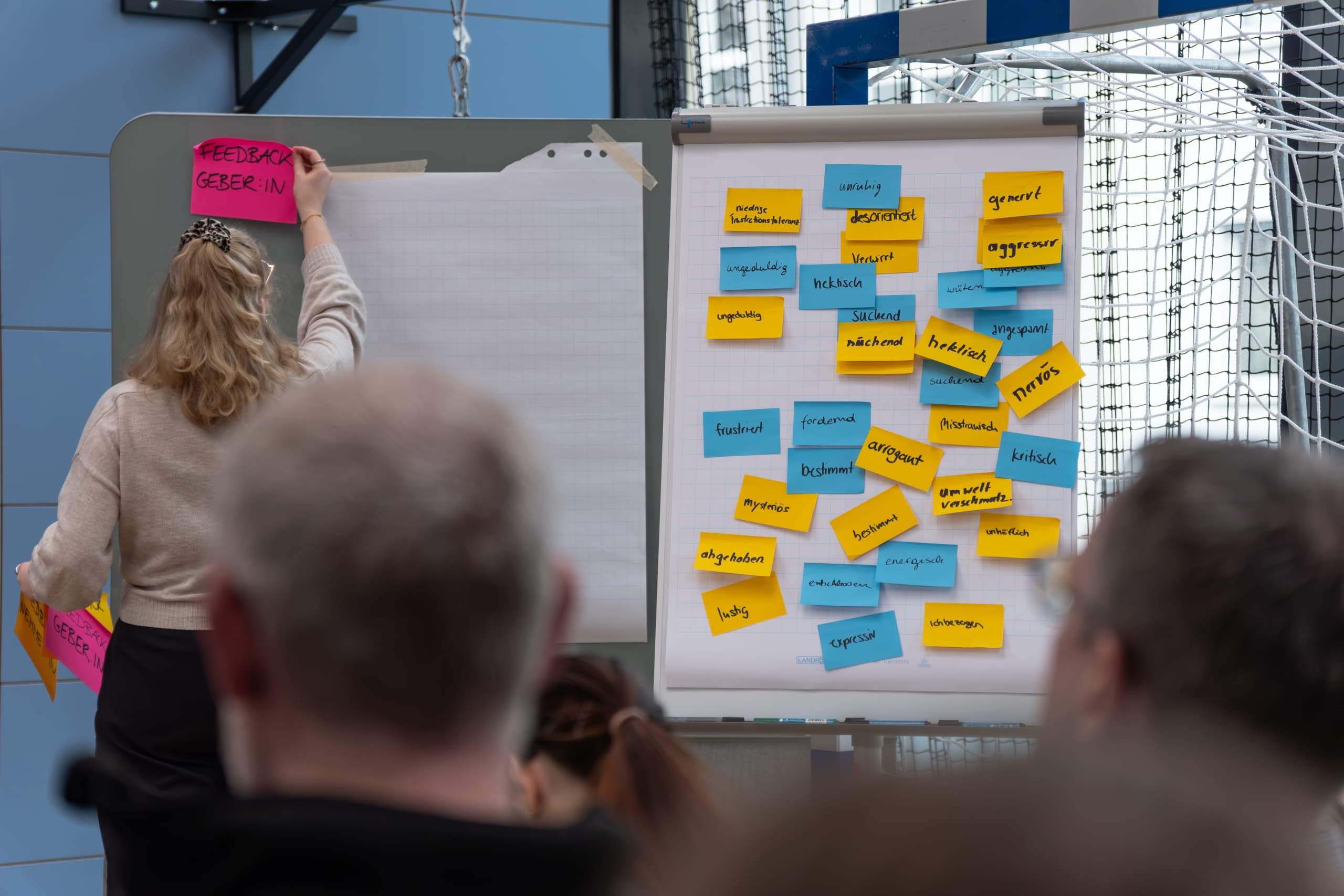 Workshop-Teilnehmer ordnen farbige Notizzettel an einer Pinnwand zur Ideensammlung