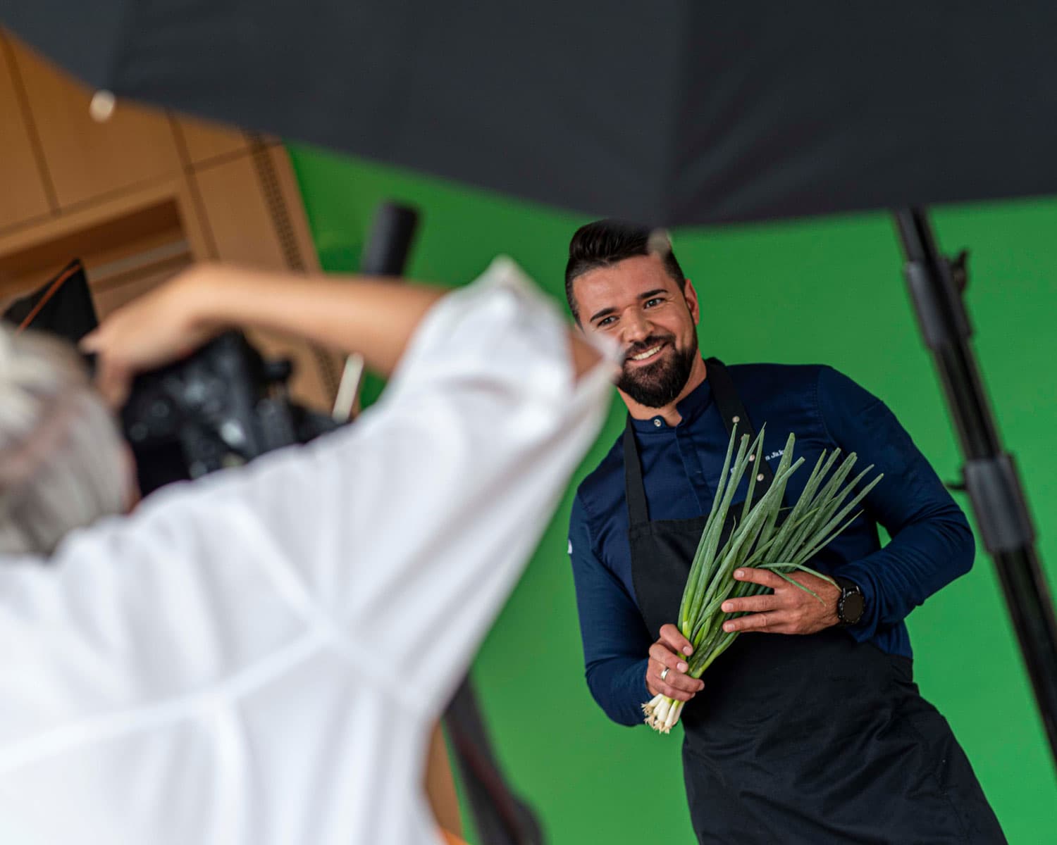 Koch mit Lauch vor Green Screen während Fotoshooting für heristo Karrierewebsite