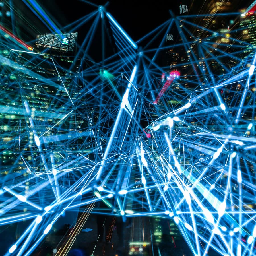 Leuchtendes digitales Netzwerk aus blauen Verbindungslinien uber einer Stadtsilhouette bei Nacht