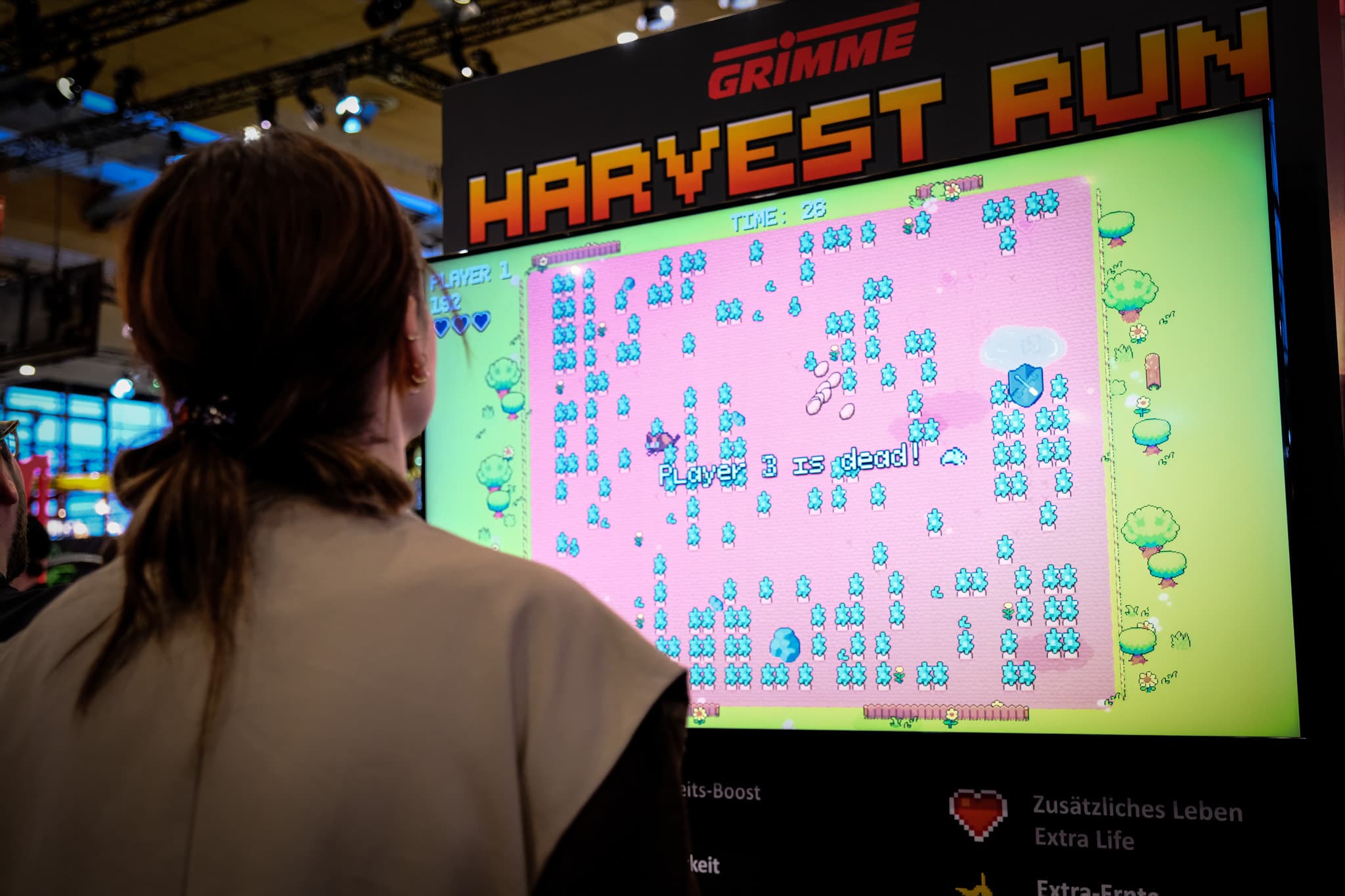 Besucherin der Agritechnica spielt das Grimme-Branded-Game 'Harvest Run' am Messestand – auf dem Bildschirm ist der Game-Over-Screen zu sehen