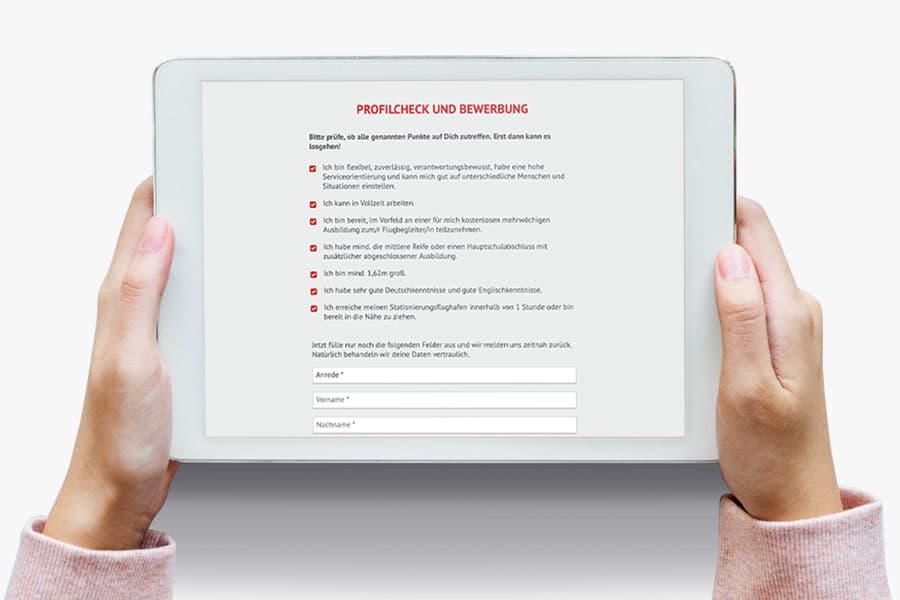 Hände halten ein iPad mit dem GVO-Bewerbungsformular 'Profilcheck und Bewerbung' für Flugbegleiter