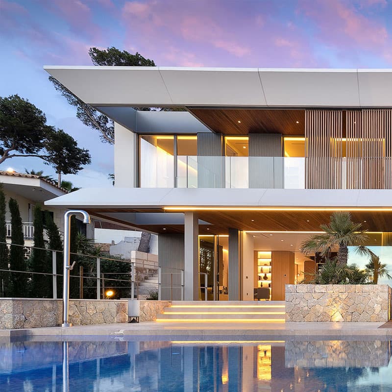 Moderne Luxusvilla auf Mallorca mit Pool, Holzfassade und warmem Lichtambiente im Abenddämmer