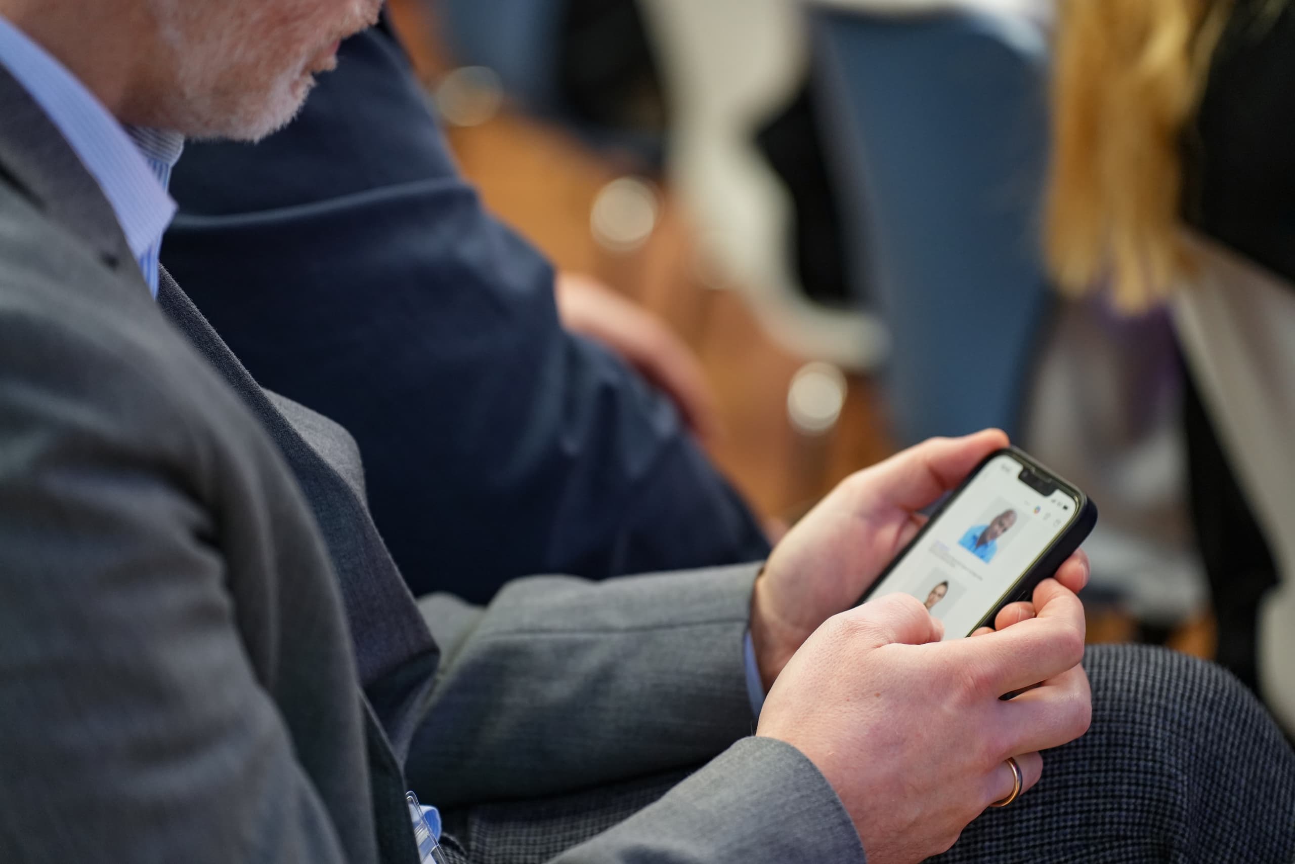Mann im Anzug schaut auf sein Smartphone bei einer Veranstaltung zum Thema Future of Customer Care