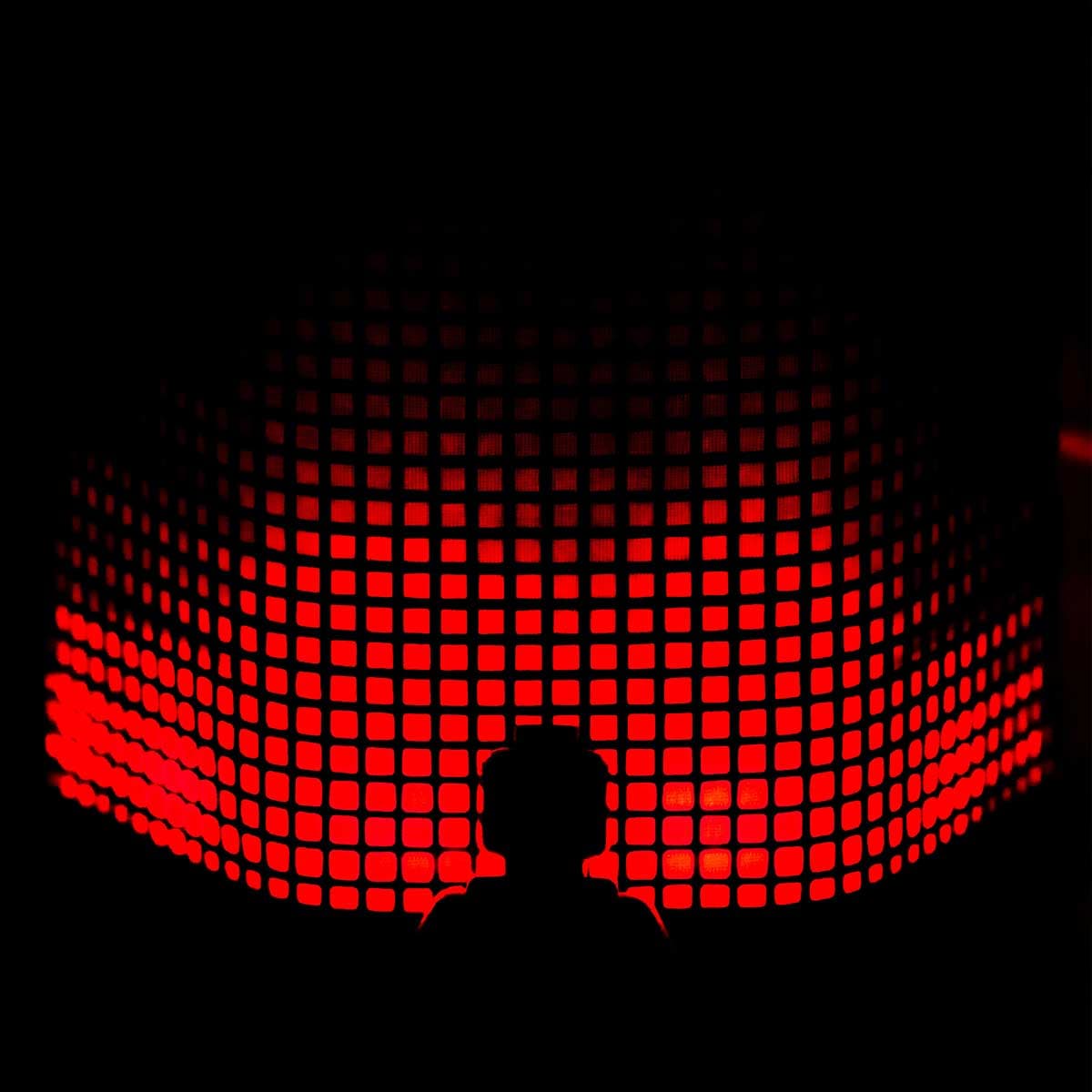 Silhouette einer Person vor einer rot leuchtenden Pixel-Wand als Sinnbild für Hidden Champions im Daten-Marketing