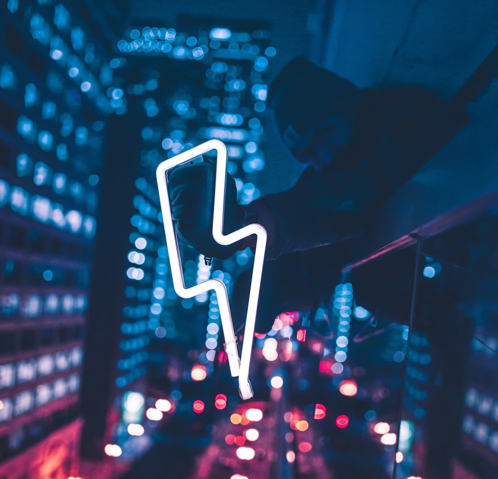 Neon-Blitzsymbol vor nächtlicher Stadtkulisse – steht für Geschwindigkeit und Innovation im KI-gestützten Customer Care