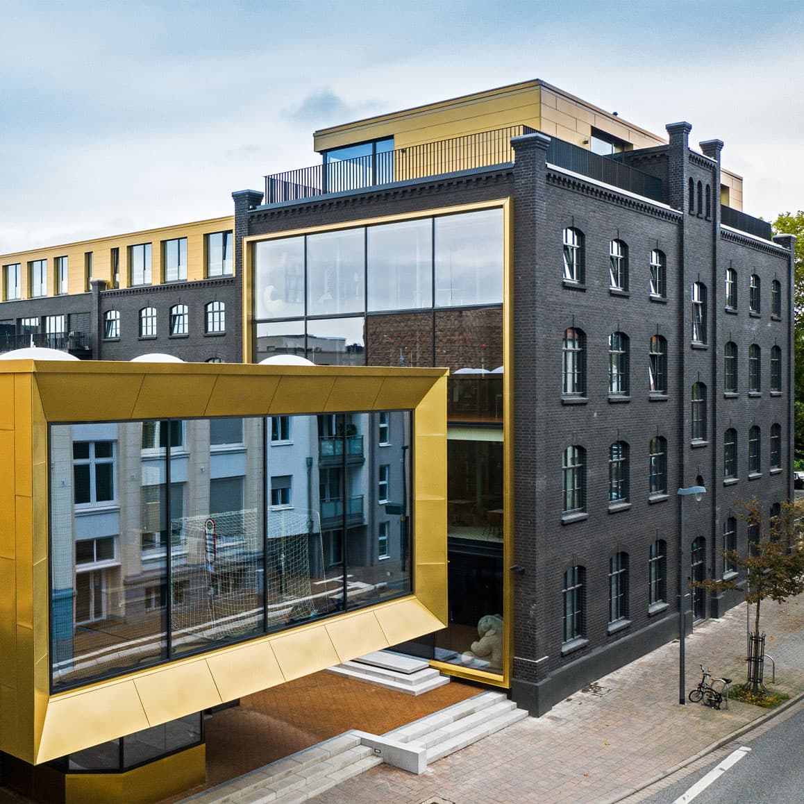 MUUUH!-Büro im Hageloft: Moderne Architektur mit gelbem Glasanbau und Backsteinaltbau