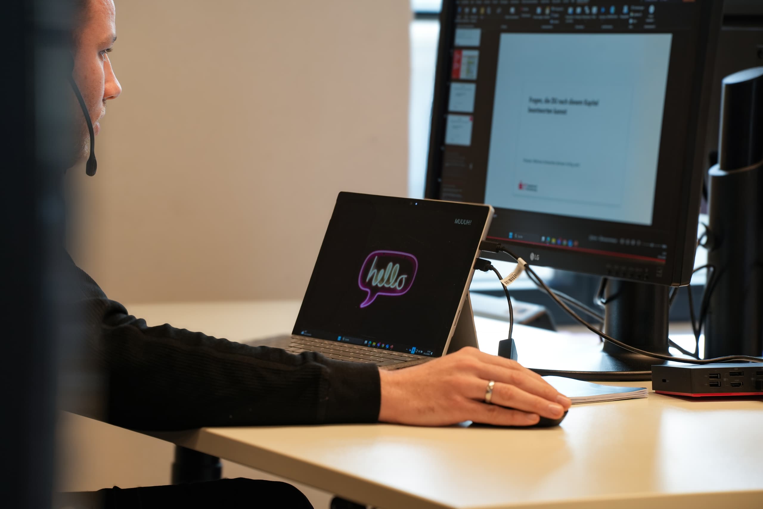 Kundenservice-Mitarbeiterin mit Headset arbeitet an Laptop und Monitor – Symbol für Conversational AI im modernen Kundendialog