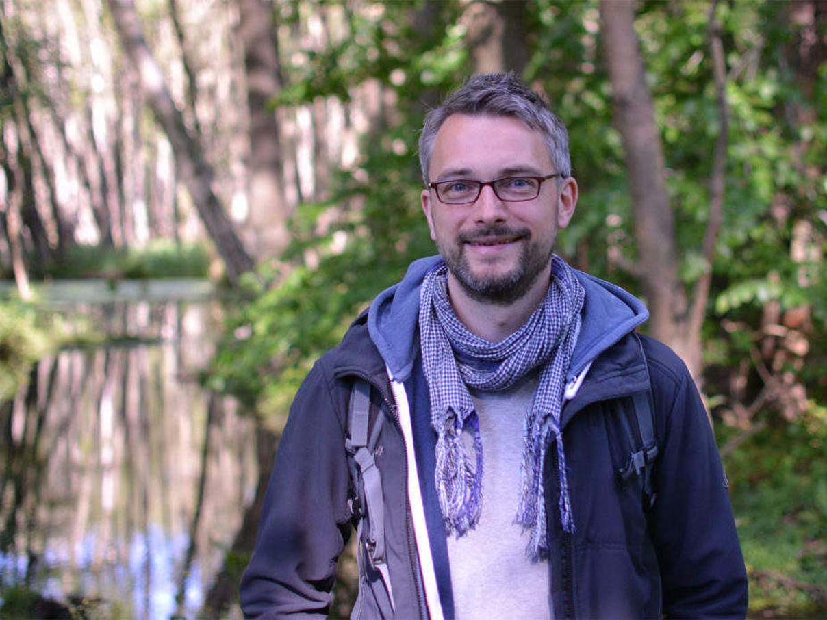 Marcel Gluschak, Leitung WWF Jugend, steht in einem lichten Wald vor einem Gewässer