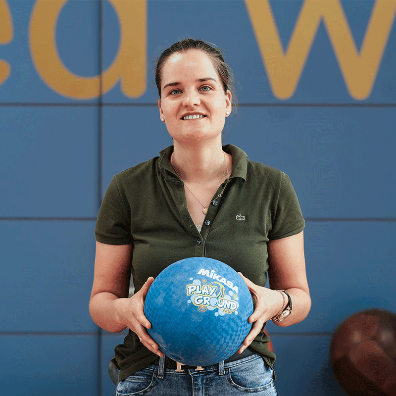 Charlotte Arnoldi hält einen blauen Mikasa Playground-Ball und lächelt in die Kamera