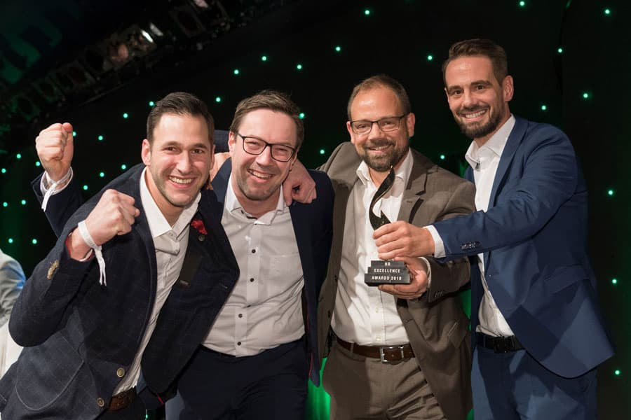 Vier Männer feiern gemeinsam den Gewinn des HR Excellence Awards 2018 für die Recruiting-Kampagne von MUUUH! und List AG