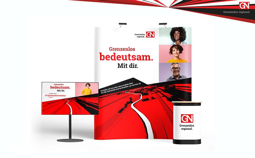 Messestand der Grafschafter Nachrichten mit Roll-ups, Monitor und Theke im rot-weißen Corporate Design