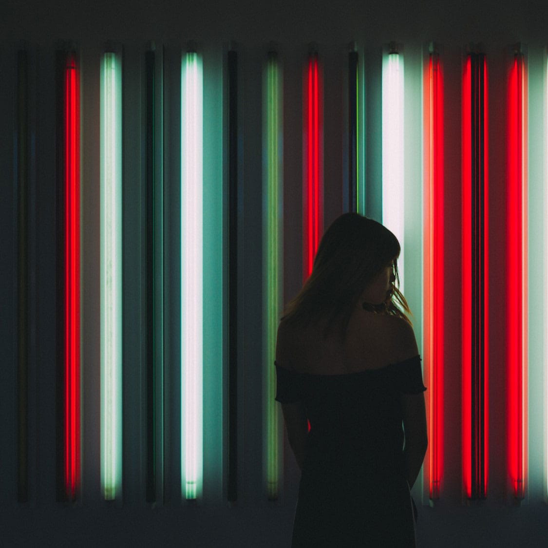 Silhouette vor farbigen Neon-Röhren symbolisiert moderne Beleuchtungstechnologie
