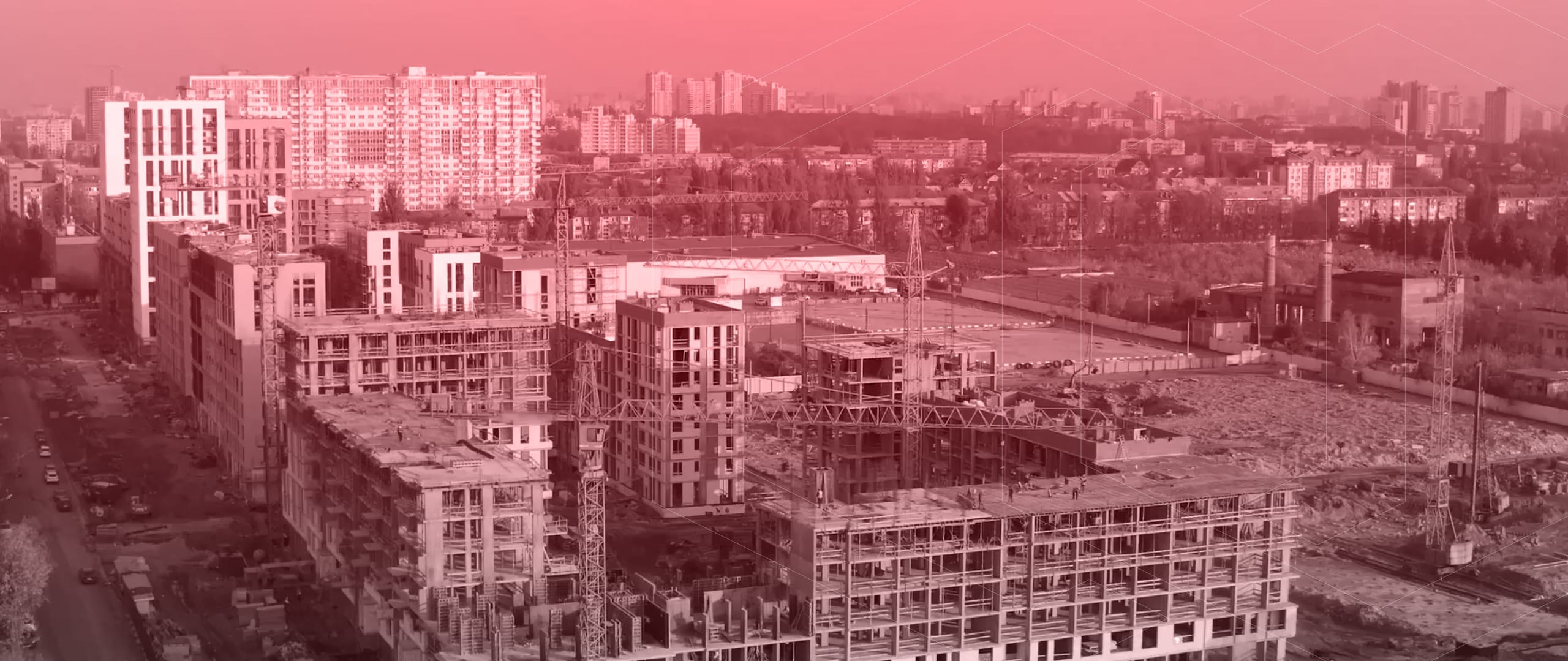 Stadtlandschaft mit Gebäuden im Rohbau und Abriss unter rosa-getöntem Himmel