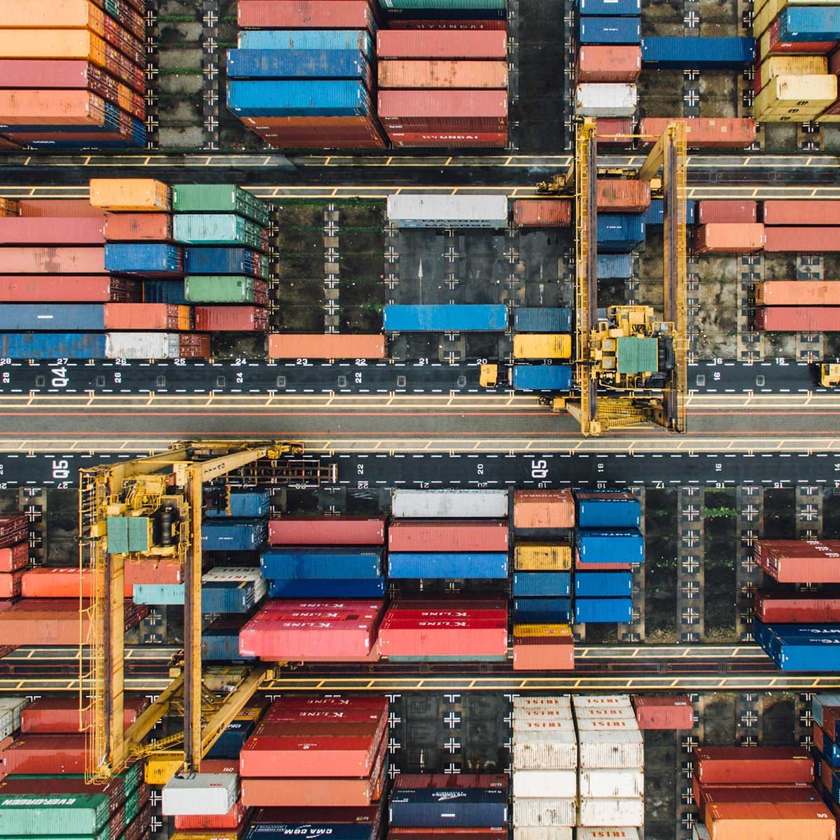 Luftaufnahme eines Containerterminals mit Portalkränen und farbigen Frachtcontainern