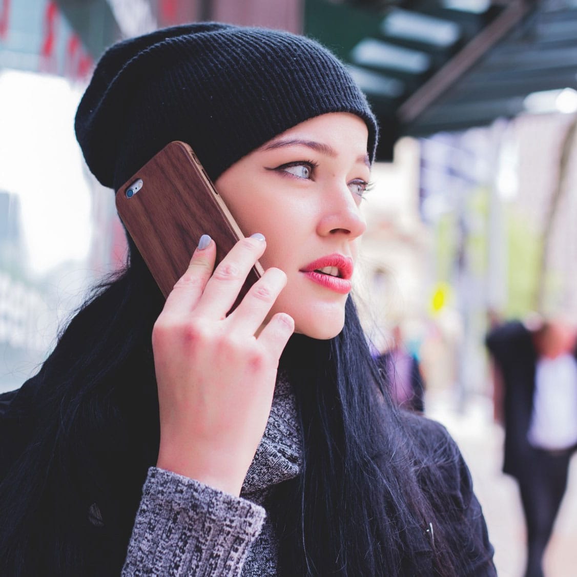 Junge Frau mit schwarzer Mütze telefoniert mit dem Handy – symbolisiert optimierte Gesprächsführung im Kundenservice