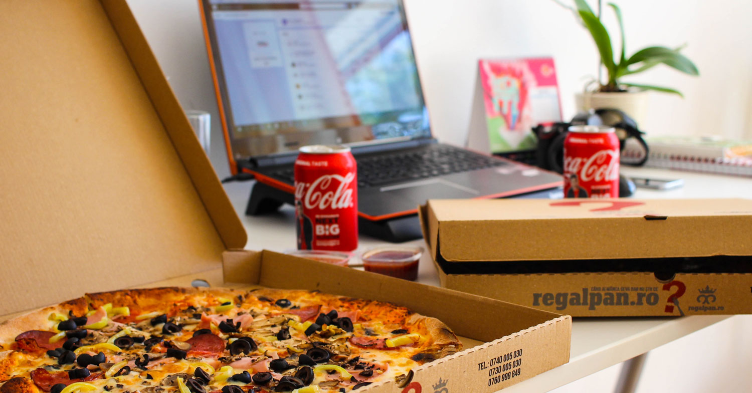 Eine Pizza mit Laptop und Cola