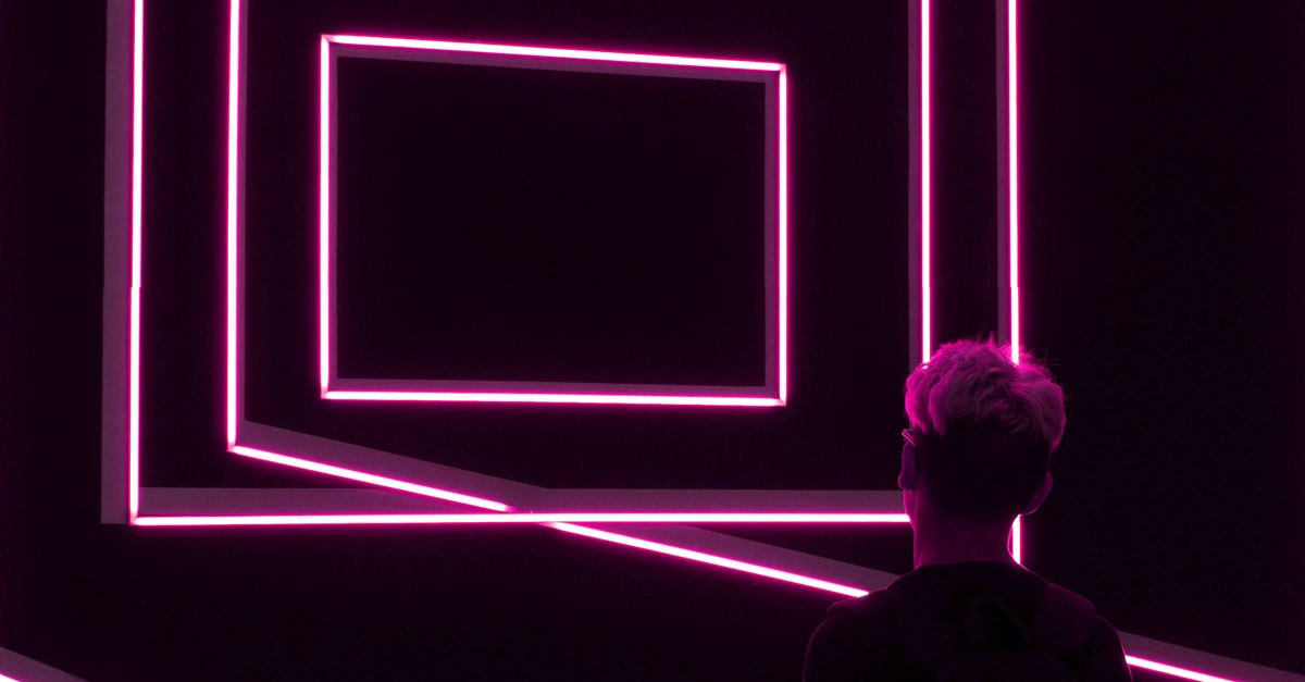 Person steht vor Neon Rahmen