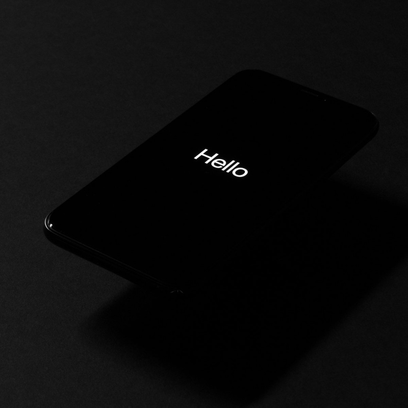 Schwarzes Iphone mit einem Hello Schriftzug auf dem Bildschirm