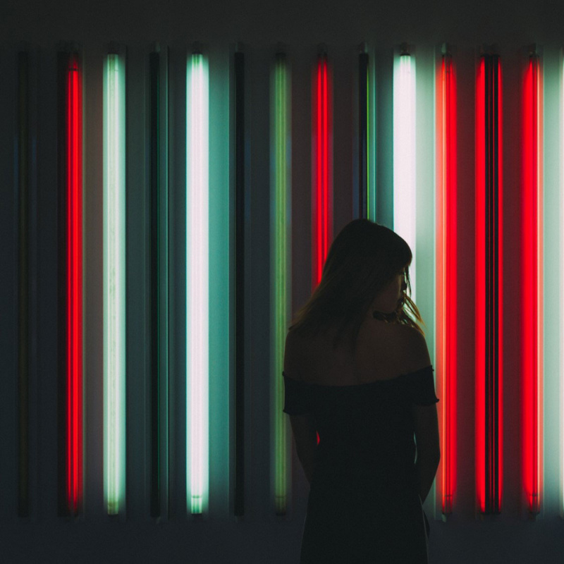 Eine Frau steht vor rotem und schwarzen Neonlicht 