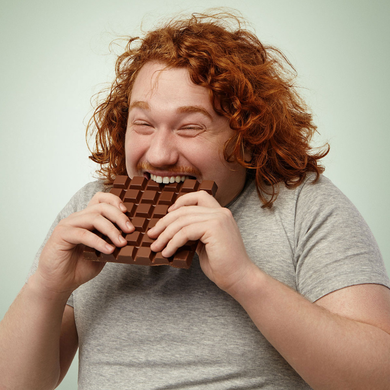 Rothaariger Mann isst eine Tafel Schokolade