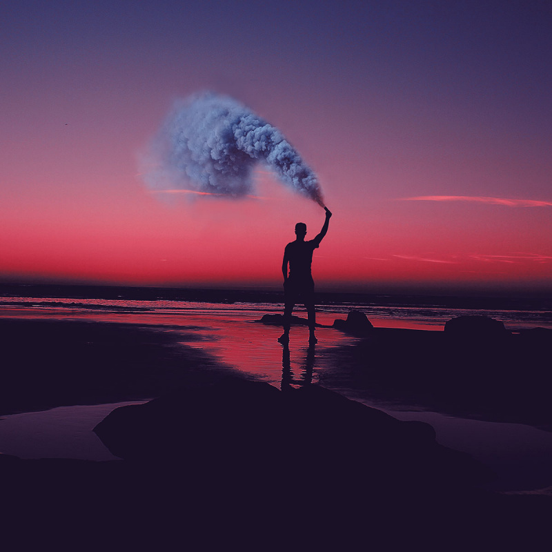 Mann mit Rauchkanone im Sonnenuntergang