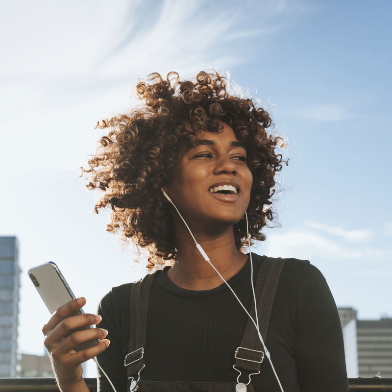 Junge Frau hört Musik mit Kopfhörern von ihrem Handy