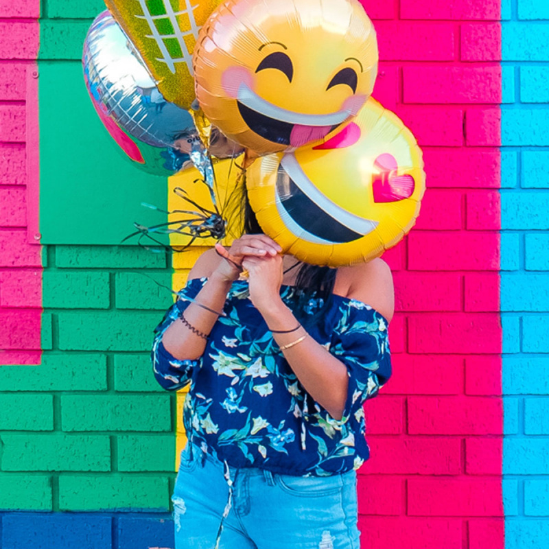 Mädchen mit Ballons in Emoji-Form