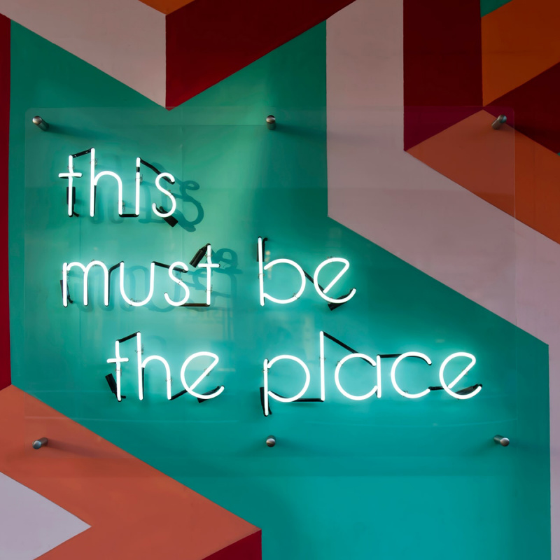 Eine bunte Wand mit dem neon Schriftzug 'this must be the place'