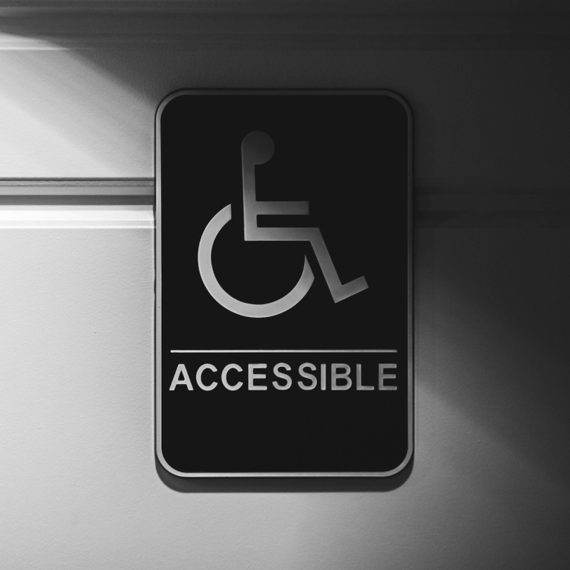 Schild mit Rollstuhl und der Unterschrift Accessible an einer Wand