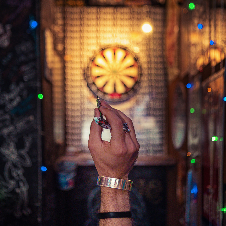 Hand mit Dartspfeil vor Dartscheibe