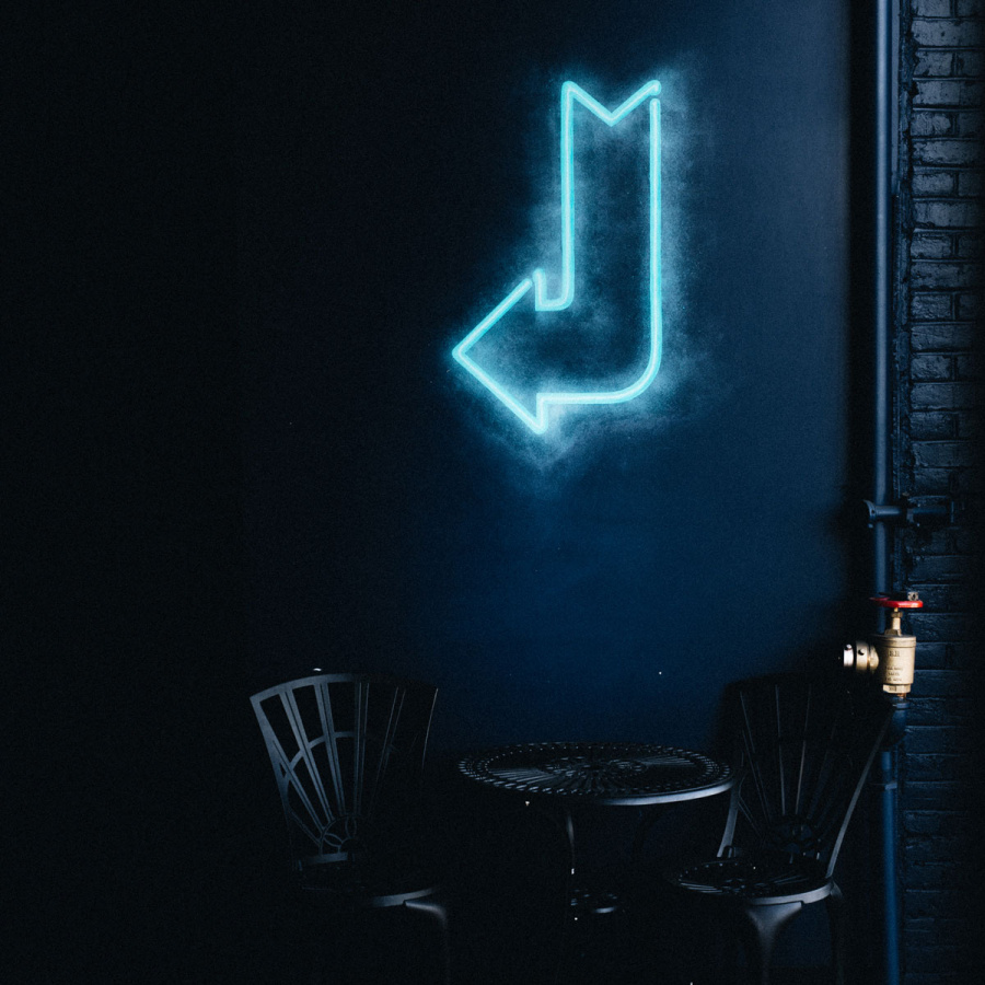 Leuchtender Neon Pfeil über Tisch mit zwei Stühlen