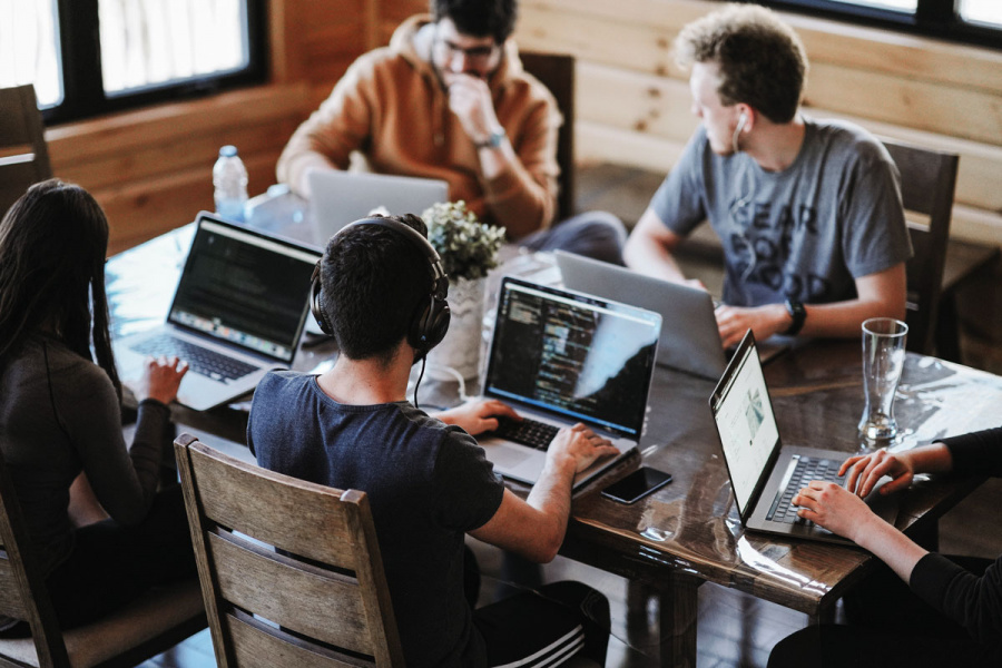 Team mit Laptops arbeitet gemeinsam am Tisch